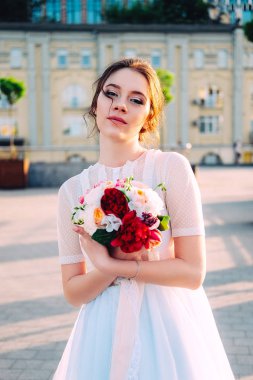 Gelin Gelinlik ve buket sokakta duran güzel günbatımı portresi