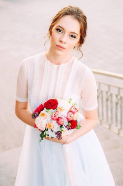 Sevimli Genç gelin gelin buketi ile peonies yapılan, gül, frezya çiçek ve giyen Beyaz tül düğün ayakta merdiven üzerinde giysi