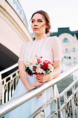 Sevimli Genç gelin gelin buketi ile peonies yapılan, gül, frezya çiçek ve giyen Beyaz tül düğün ayakta merdiven üzerinde giysi