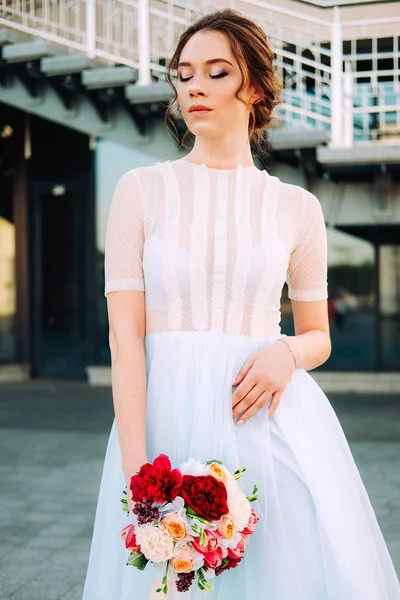 美丽的日落肖像新娘的婚纱礼服和花束站在街上 — 图库照片