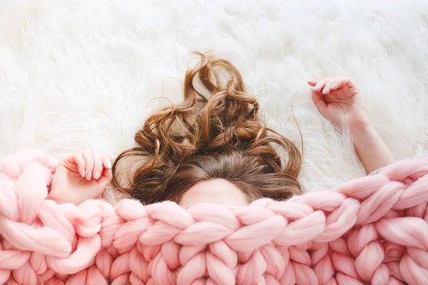 长棕色头发的年轻妇女睡在温暖的针织桃颜色投掷毯子之下 — 图库照片