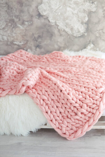 Large knitted pink throw blanket for loft apartment. Interior design furnishing.