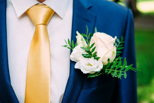 穿着深蓝色西装和黄色领带的新郎身穿白色玫瑰纽扣花束 — 图库照片