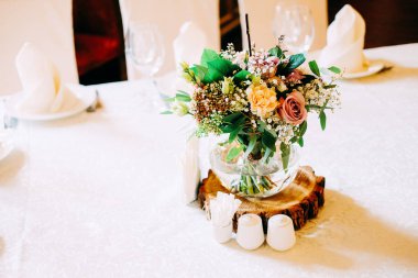 Düğün masa çiçek dekorasyonu. Cam vazo ile tablo sayı konuklar yeşillik, gül, lisianthus ve diğer çiçekler için.