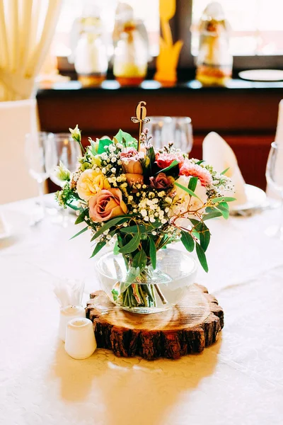 婚礼桌花装饰 带有绿叶 桔梗和其他花卉的客人桌号的玻璃花瓶 — 图库照片