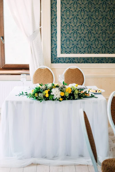Elegant bride and groom table setting for the wedding with candlestick centerpiece in yellow and green colors