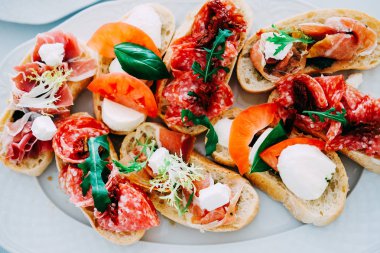 Jambon, sosis, domates, mozzarella peyniri, otlar ile İtalyan bruschetta snack restoran beyaz tabakta servis