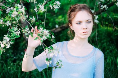 Sakin ve güzel genç kadın bahçedeki şeffaf mavi elbise