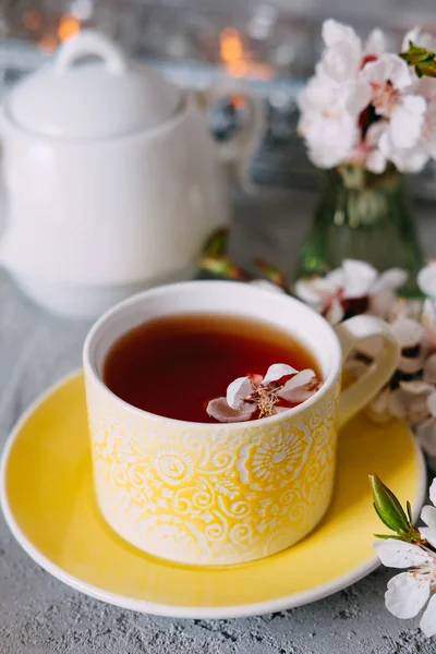 Tè servito in una tazza da tè gialla e piattino decorato con f primavera — Foto Stock