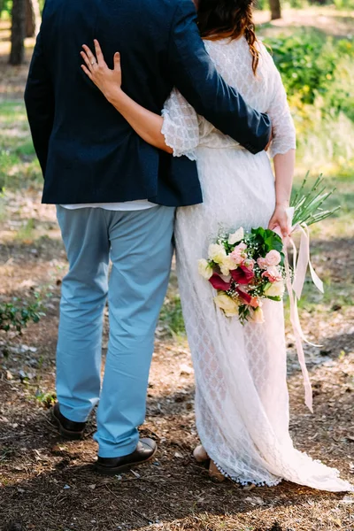 Recién casados pareja de amantes abrazando y sosteniendo flores — Foto de Stock
