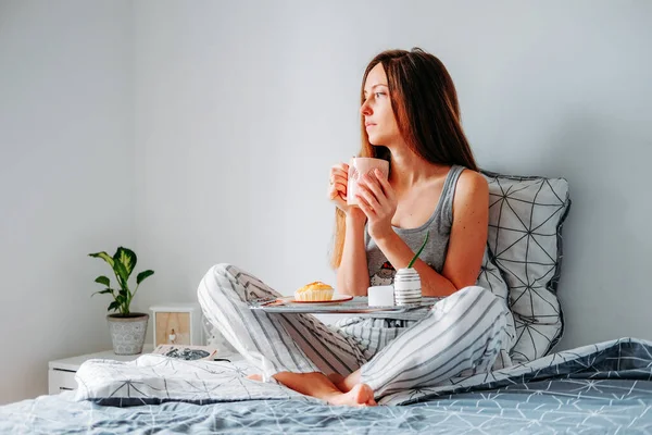 Woman in cozy pajamas having her breakfast in bed