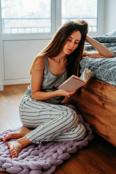 Pijamalı Evde Oturmuş Kitap Okuyan Sert Bir Genç Kadın — Stok fotoğraf