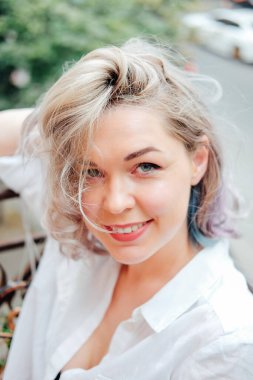 Genç bir kadın yaz balkon bahçesinde iç çamaşırı ve tişörtle dinleniyor.