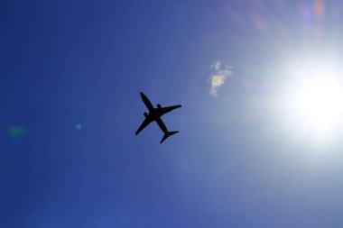 Güneşin parladığı mavi bir gökyüzünde uçan bir jet uçağının silueti