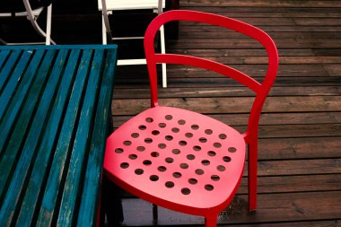 Kırmızı çelik sandalyeli yağmurlu bir teras