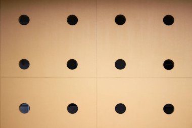 Bir sürü yuvarlak deliği olan sarı duvar.