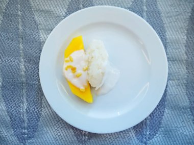 Hindistan cevizi sütü beyaz plaka üzerinde yapışkan pirinç ile tatlı mango.