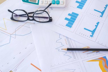 iş ofis masası, çalışma alanı ile eyeglassed ve kalem, hesap makinesi, rapor grafik ahşap masa üstünde laptop.