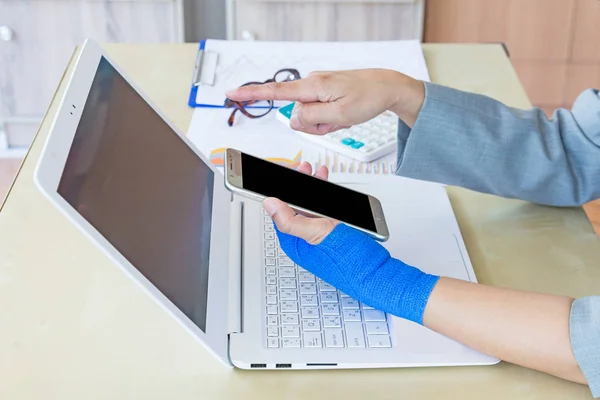kadın mavi elastik bandaj ile el üstünde Laptop ofiste çalışan yaralı.