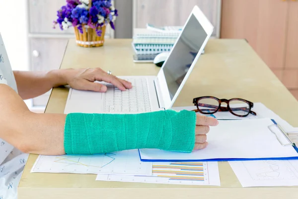yeşil ile çalışan kadın laptop ofis, kırık el odaklanmak çalışma kolundaki döküm.