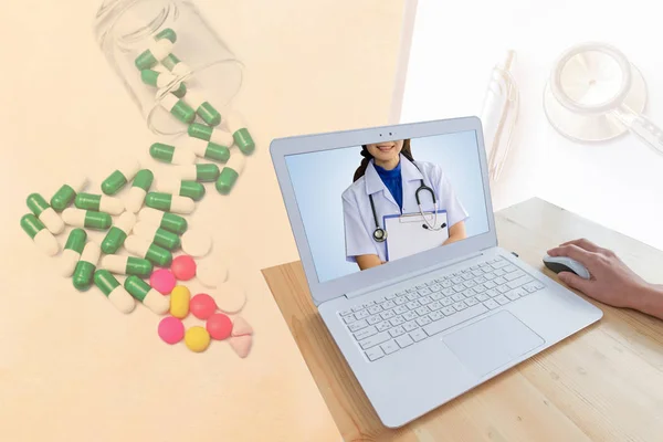 Beyaz Tıbbi üniforma ve modern dizüstü bilgisayar ve ahşap masa bulanık hap ve kapsül stetoskop tıbbi grafik, sağlık ve eczane konsepti ile izole fare kullanarak el ile Stetoskoplar giyen doktor kadın.