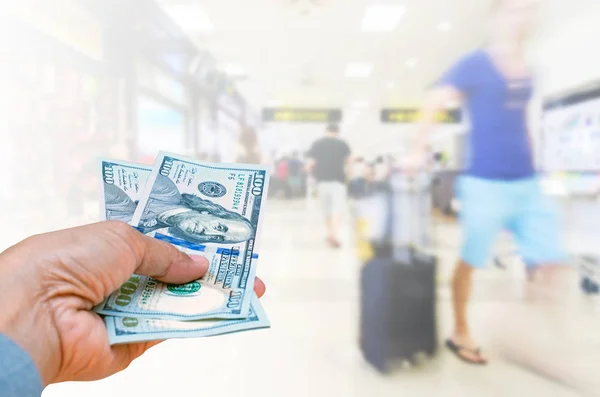 İş kadını Amerikan Doları para birimi üzerinde arka plan bulanık yolcuları Havalimanı terminal Bagaj ile yürüme izole tutan el, maliyet kavramı seyahat.