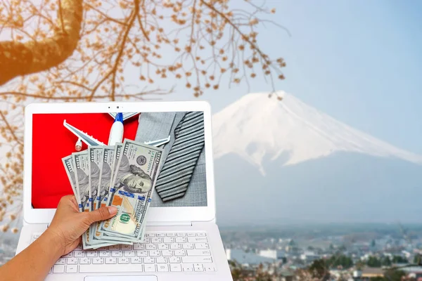Fuji Dağı Japonya'da iş kadın el uçak, kravat ve takım elbise ile Amerikan Doları para birimi üzerinde izole kırmızı bavul üzerinde tutarak bulanık, maliyet kavramı seyahat.
