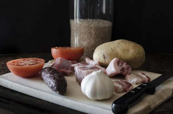 Fırında pilav, domates, patates, domuz pastırması, domuz kaburgası ve kan sosisi.