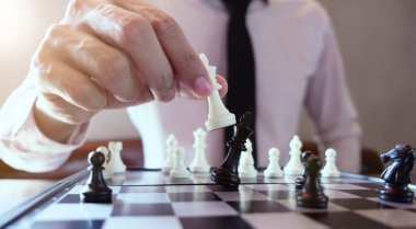 Closeup photo of businessman playing chess and beating black kin