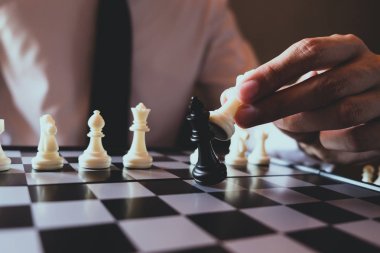 Closeup photo of businessman playing chess and beating black kin