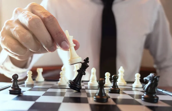 Closeup photo of businessman playing chess and beating black kin