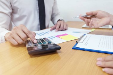 Business man is using a calculator to calculate the numbers with