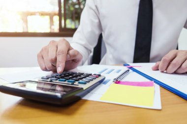 Businessman is using a calculator to calculate the numbers