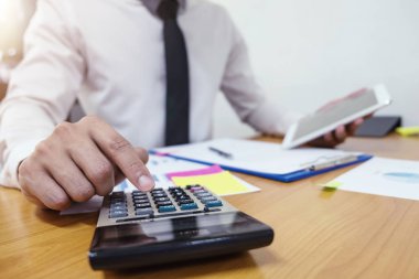 Businessman is using a calculator to calculate the numbers