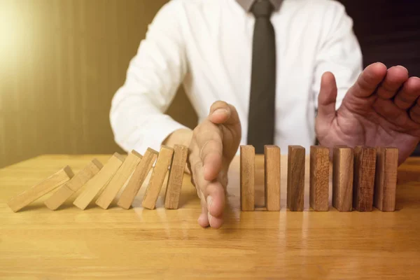 Hand of businessman is stoping falling wooden domino effect from — Stock Fotó