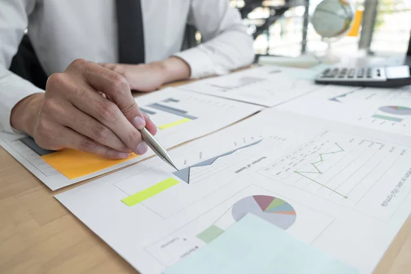 Businessman is analyzing business plans on the table in the offi