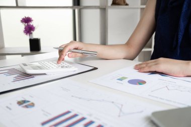 İş kadınları odadaki grafikten elde ettikleri geliri ve ev, finans ve muhasebe kavramlarından elde ettikleri gelirleri hesaplıyorlar..