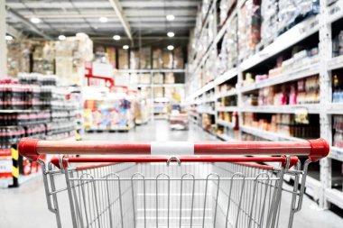Marketteki bulanık arka planı olan boş kırmızı alışveriş arabası, alışveriş konsepti..