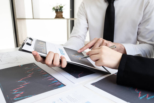 Two business people are discussing and analyze strategy of investment from the stock graph in the office room, Business and finance concept.