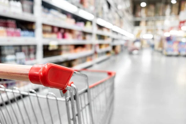 Marketteki bulanık arka planı olan boş kırmızı alışveriş arabası, alışveriş konsepti..