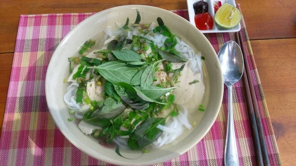 Üst sosu, kireç ve kaşık ile tabloda görülen Pho Ga Vietnamca tavuk şehriye çorbası