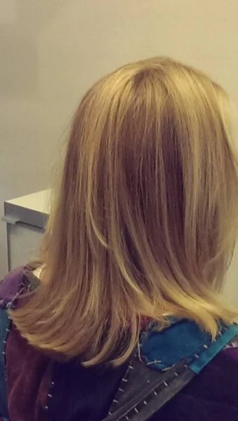 Saç salonunda tedavi edildikten sonra yıkanmış, tedavi edilmiş ve şık güzel pürüzsüz sarı saçlı kadın; arkasındaki görünüm