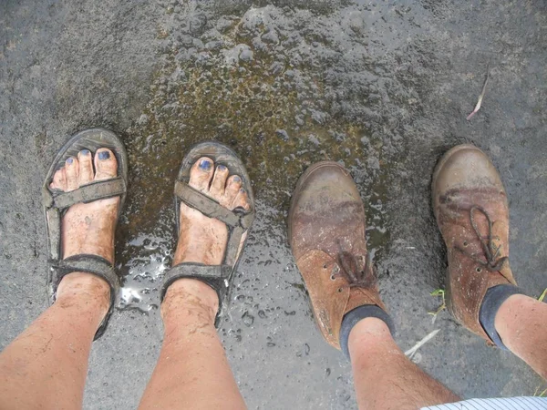 İki çift çamurlu ayak (bir erkek, bir kadın) yağışlı sezon ıslak bir zam sonra tropikal Bali, pis ayaklarına bakıyordu