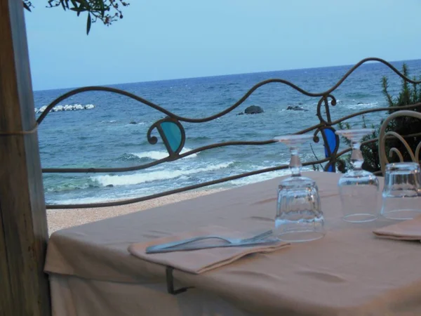 Akdeniz 'in plajının hemen yanında romantik bir akşam yemeği için hazır olan sahil restoranında nevresim ve gözlüklerle set masa