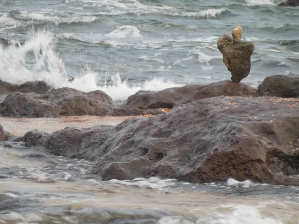 Yalnız kule iki kaba taş üstüne taş, kaba deniz dalgaları arka planda ile İtalya Sardinya Adası plaj sahil şeridi yığılmış