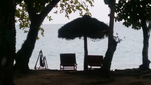 Sakin tropikal plaj gölgeli ağaçlar ve siluetleri iki şezlong ve şemsiye ve hamak, Phu Quoc, Vietnam