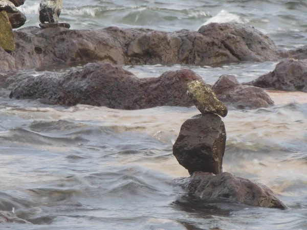 İki kayalar denizin içinde bir kaya arka planda daha fazla taşlarla üstüne yığılı Kulesi