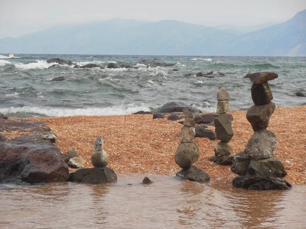 Rough taşlar yakınındaki kıyı şeridi kumlu plaj, Sardinya Adası İtalya ile dalgalı deniz ve dağlar arka planda yığılmış dört kuleleri