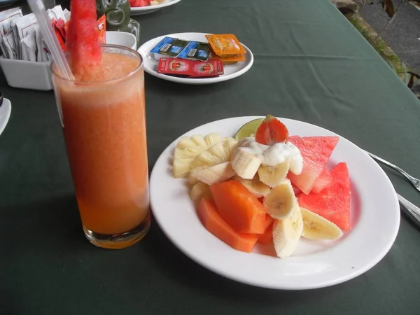 Karpuz, muz, ananas ve papaya ile sağlıklı tatil kahvaltı olarak taze meyve suyu ile tabloda tabakta tropikal taze meyve salatası