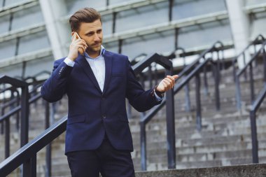 Açık havada, cep telefonundan bir işadamı konuşurken iş elbiseli bir adam